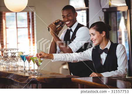 Female bartender garnishing cocktail with olive Female bartender garnishing cocktail with olive 31557753