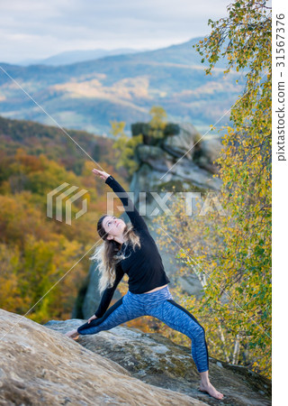 Woman is practicing yoga on the top of mountain 31567376