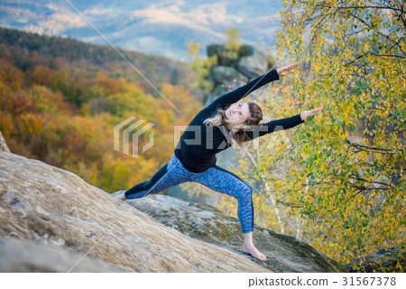 Woman is practicing yoga on the top of mountain 31567378
