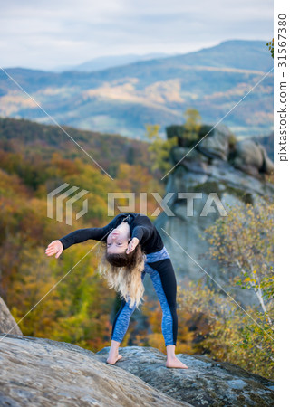 Woman is practicing yoga on the top of mountain Woman is practicing yoga on the top of mountain 31567380