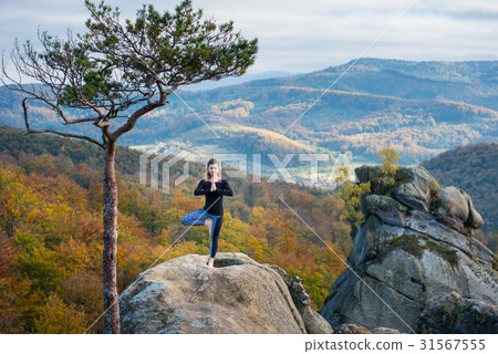 Woman is practicing yoga on the top of mountain 31567555