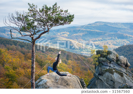 Woman is practicing yoga on the top of mountain 31567560
