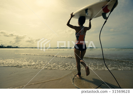 young woman surfer with surfboard ready to surf 31569628