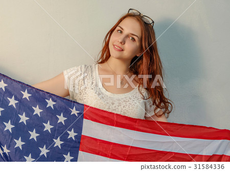 Young woman with american flag in hands looking at 31584336