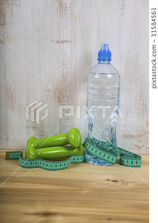 Dumbbells and a bottle of water on a wooden table. 31584561