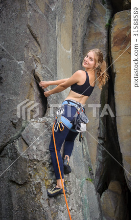 Female climber climbing with rope on a rocky wall Female climber climbing with rope on a rocky wall 31588589