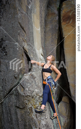 Female climber climbing with rope on a rocky wall Female climber climbing with rope on a rocky wall 31588590