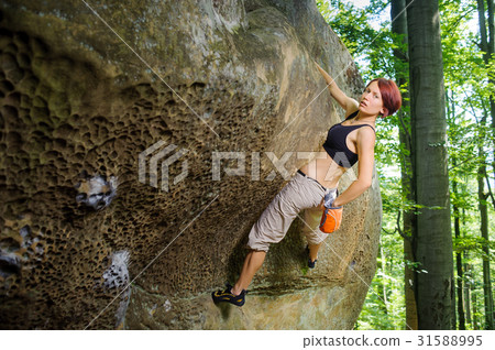 Female climber climbing on a rocky wall 31588995