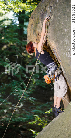 Female climber climbing with rope on a rocky wall Female climber climbing with rope on a rocky wall 31589021