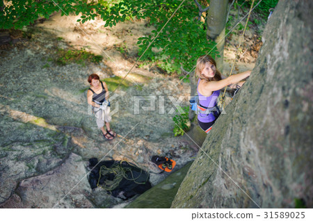 Female climber climbing with rope on a rocky wall 31589025