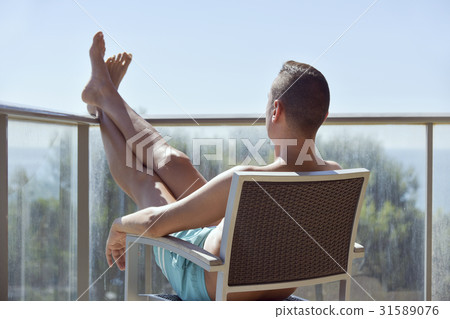 young man sun tanning in a chair 31589076