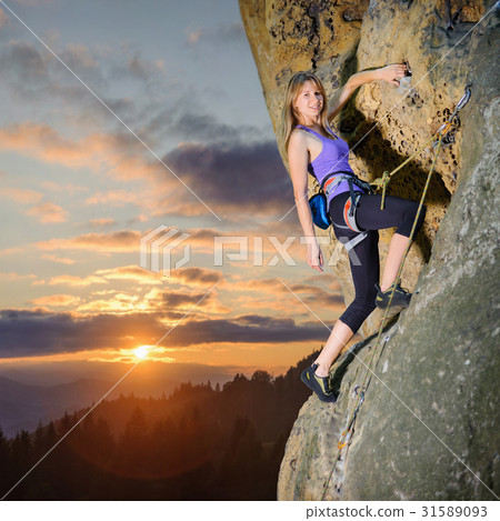 Female climber climbing with rope on a rocky wall Female climber climbing with rope on a rocky wall 31589093