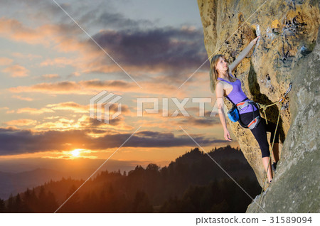 Female climber climbing with rope on a rocky wall Female climber climbing with rope on a rocky wall 31589094