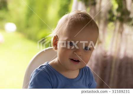Adorable blue-eyed toddler sitting outdoor in a 31589231
