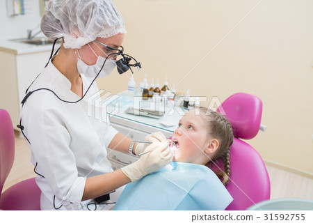 Young female dentist wearing in loupe binoculars Young female dentist wearing in loupe binoculars 31592755
