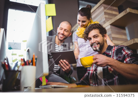 Businessman with coworkers at computer desk in office Businessman with coworkers at computer desk in office 31594375