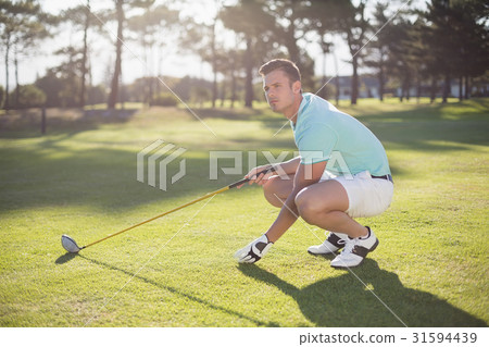 Full length of golfer man placing golf ball on tee 31594439