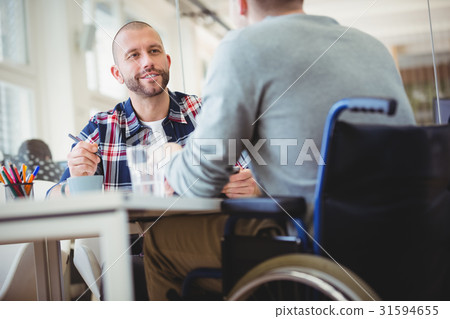 Businessman discussing with handicap colleague in office 31594655
