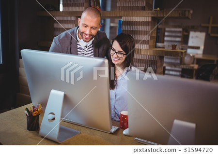 Business people smiling while looking at computer Business people smiling while looking at computer 31594720