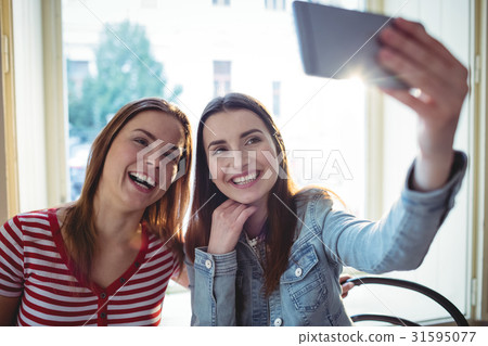 Cheerful female friends taking selfie at coffee shop Cheerful female friends taking selfie at coffee shop 31595077