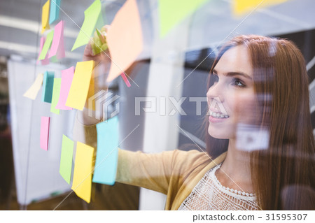 Attractive businesswoman writing on sticky notes 31595307