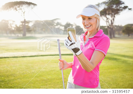 Woman golfer looking her mobile phone Woman golfer looking her mobile phone 31595457