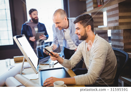 Male creative coworkers discussing over computer Male creative coworkers discussing over computer 31595591