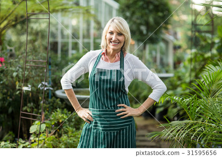 Mature woman standing with hand on hip at greenhouse 31595656