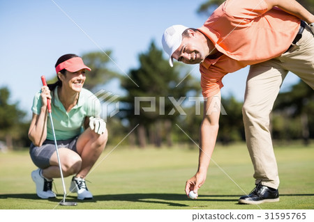 Portrait of man removing golf ball from hole Portrait of man removing golf ball from hole 31595765