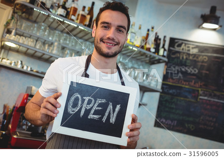 Portrait of confident barista holding blackboard at cafeteria Portrait of confident barista holding blackboard at cafeteria 31596005