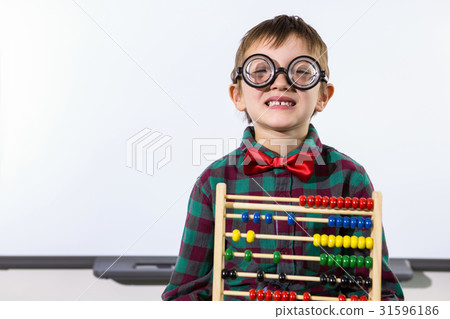 Cute boy with abacus against whiteboard in classroom Cute boy with abacus against whiteboard in classroom 31596186