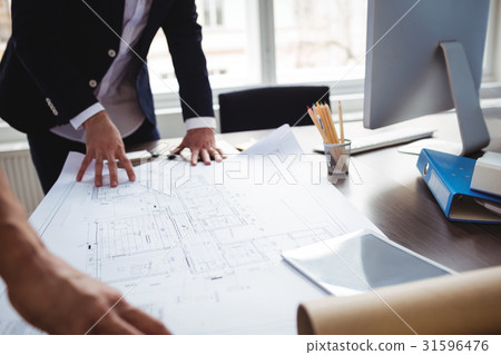 Interior designer discussing blueprint with coworker 31596476