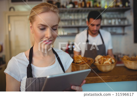 Waitress using tablet computer with colleague in background 31596617