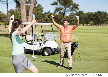 Happy golfer couple with arms raised Happy golfer couple with arms raised 31596669
