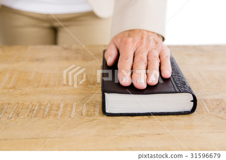Midsection of woman with hand on bible Midsection of woman with hand on bible 31596679