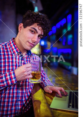 Portrait of man holding beer glass at bar counter Portrait of man holding beer glass at bar counter 31596747