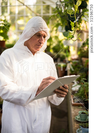 Male scientist writing on clipboard while examining plants 31596750