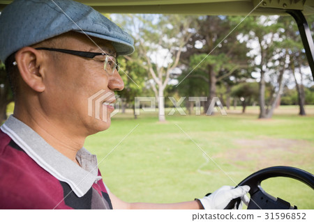Golfer driving golf buggy 31596852