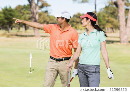 Smiling golfer man pointing while standing by woman 31596853