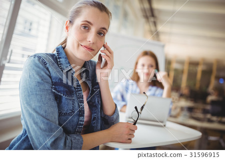 Smiling businesswoman using mobile phone at creative office Smiling businesswoman using mobile phone at creative office 31596915