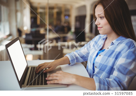 Young businesswoman working on laptop in creative office Young businesswoman working on laptop in creative office 31597085
