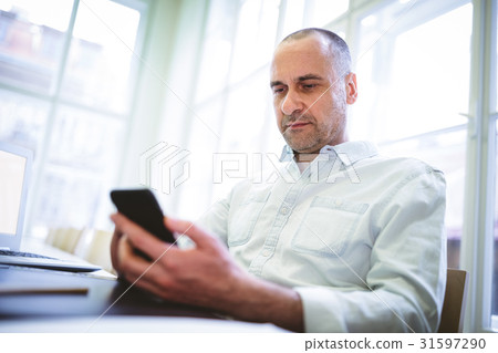 Serious businessman using mobile phone Serious businessman using mobile phone 31597290