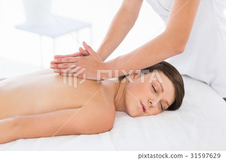 Masseuse giving back massage to naked woman Masseuse giving back massage to naked woman 31597629