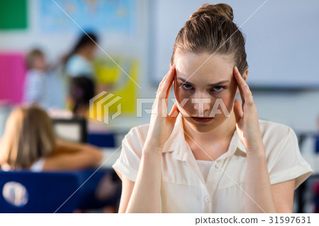Depressed female teacher touching her head 31597631