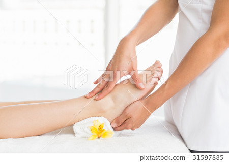 Midsection of masseur giving foot massage to woman 31597885