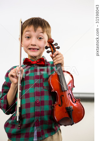 Cute boy holding violin with bow in classroom Cute boy holding violin with bow in classroom 31598043