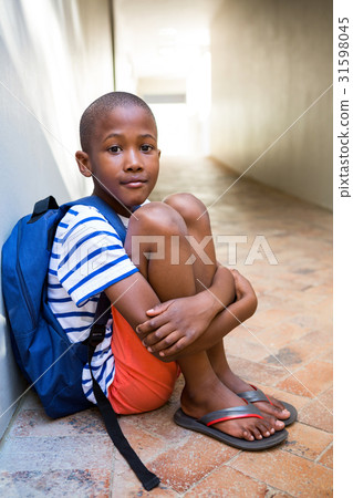 Elementary boy sitting on corridor in school Elementary boy sitting on corridor in school 31598045