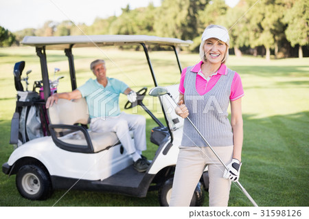 Smiling mature woman standing by man in golf buggy 31598126