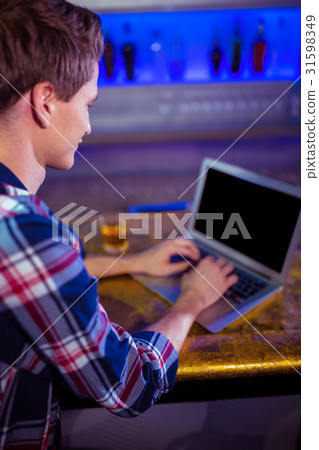 Man using laptop on bar counter 31598349