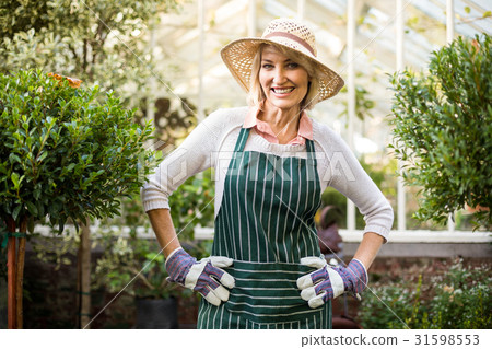 Confident female gardener standing at greenhouse Confident female gardener standing at greenhouse 31598553